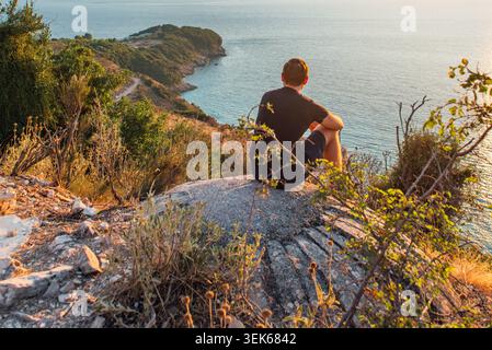 Traveler sitting on coastal bunker above Pulëbardha Beach in Albania Stock Photo
