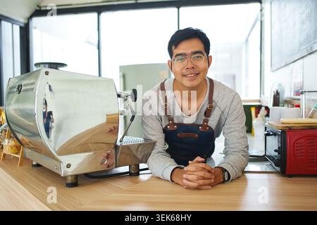 Barista Standing Beside Coffee Roasting Machine in Modern Cafe Stock Photo