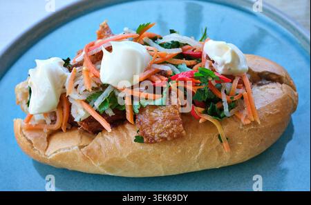 A freshly made banh mi with crispy pork served on a plate. Stock Photo