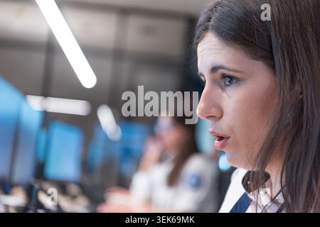 Close-up of a female security dispatcher or guard in uniform writing notes and filling out an incident report sheet or daily logbook at her desk next Stock Photo