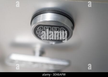A macro, selective focus shot of a metallic electronic combination lock keypad mounted on a heavy metal safe or vault door. Stock Photo