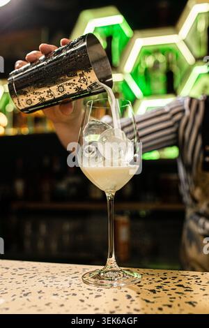 Bartender pouring cocktail into elegant glass Stock Photo