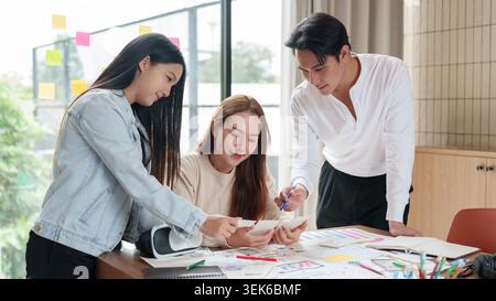 Asian design team collaborating on creative project in modern office Stock Photo