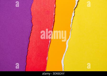 Vertical strips of torn paper. The paper strips display vibrant and contrasting colors: purple, red, orange, and yellow. Stock Photo