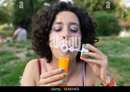 Young woman blowing soap bubbles at pride event Stock Photo
