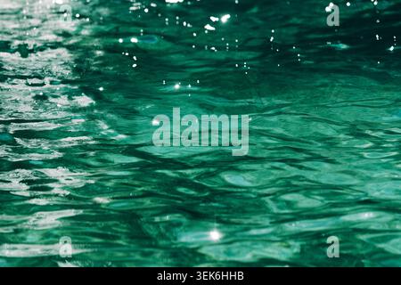 Sunlit green water surface with gentle ripples and sparkling reflections for background texture, selective focus Stock Photo