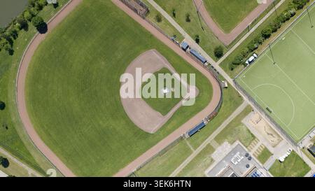 Aerial view of a baseball field with a green outfield and brown dirt infield diamond surrounded by fences and adjacent sports facilities in Houten, Ut Stock Photo