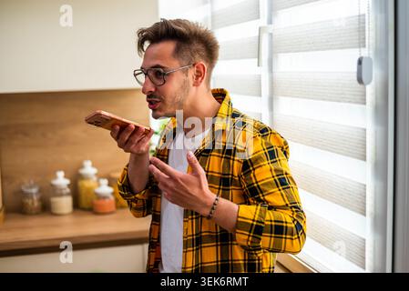 Cheerful young man is talking on mobile phone at home. Stock Photo