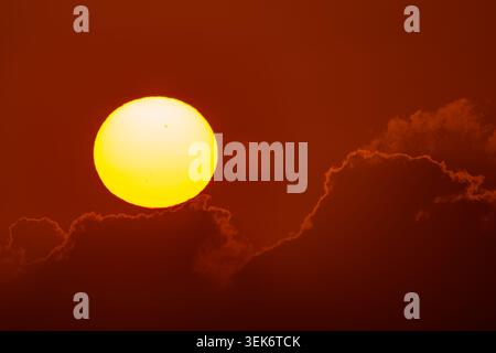 Extreme telephoto of large sunspots visible on the sun disk at a dramatic red sunset Stock Photo