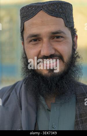 Afghan man smiling for a close-up portrait, wearing a skullcap near the blue mosque. Stock Photo