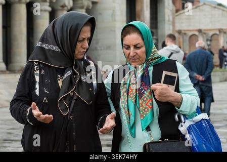 05-09-17, Tbilisi, Georgia: Two woman wearing colorful headscarves converse while walking through a plaza in Tbilisi, Georgia. Stock Photo