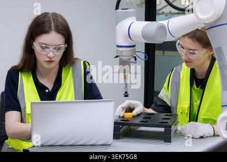 automation machine engineer woman students study and inspection control robot arm machine in robotics engineering academy at university or factory wor Stock Photo