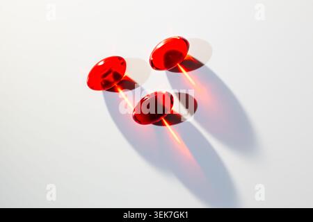 Minimalist Red Translucent Capsules with Dramatic Shadows on White Background Stock Photo
