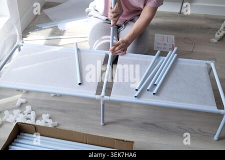 Woman assembling a white clothes drying rack on the floor Stock Photo