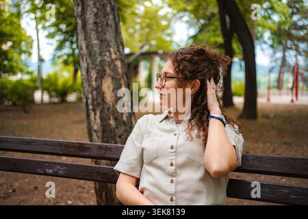 Young woman enjoying thoughtful moment sitting in park Stock Photo
