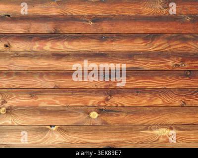 Wall of sanded logs with beautiful texture of natural wood pattern, varnished planed logs in the cladding or structure of a wall or fence Stock Photo