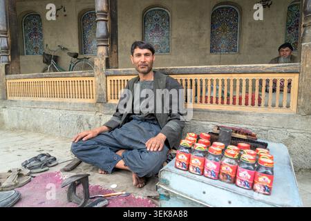Shoemaker sitting on a street with shoe polish bottles and tools in kabul. Stock Photo