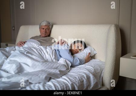 Senior man trying to make peace with stressed wife after emotional conflict gently patting on back Stock Photo