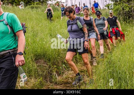 Participants in the 14th Frankenwald Hiking Marathon make their way down a grassy slope. Ludwigsstadt, Bavaria, Germany Stock Photo