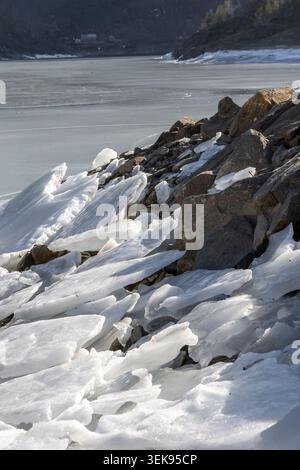 A beautiful ice cracks on the frozen surface of Onilsvatnet with a rocky shore near Tafjord village. An early spring scenery in Tafjord, Sunnmore regi Stock Photo