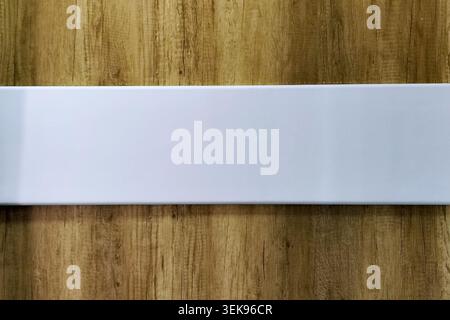 Blank white horizontal rectangular sign on a textured wooden background with copy space for text, design, or mockup. Stock Photo