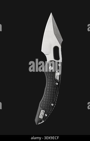 Tactical Folding Knife with Black Textured Handle on Black Background Stock Photo