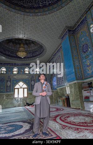 Man looking up at the decorated ceiling and walls inside a mosque Stock Photo