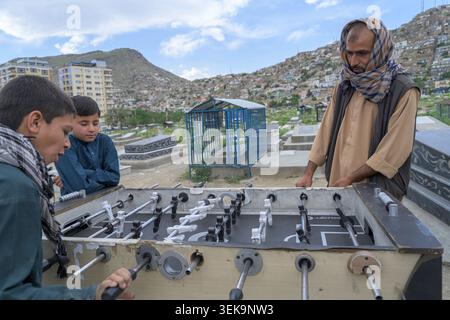People playing table football in a graveyard with a city view on the hillside Stock Photo
