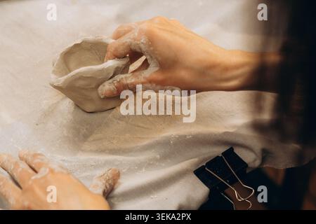 Potter hands sculpting soft clay in pottery workshop. Close-up. Hobby and pottery concept Stock Photo