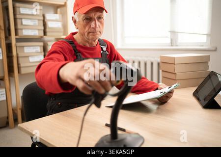 Postal employee scans parcel barcode for tracking and delivery management in a modern logistics workflow. Stock Photo