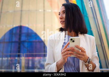 Young professional woman using smartphone in modern urban business district Stock Photo