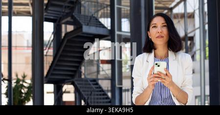 Professional woman using smartphone in modern office environment Stock Photo