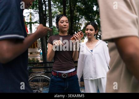 Young friends discussing and sharing information using a smartphone outdoors Stock Photo