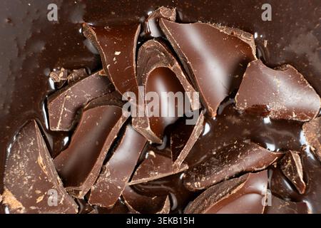 Dark chocolate chunks into liquid melted chocolate sauce background. Stock Photo