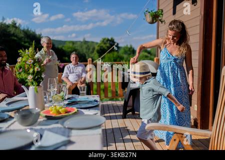Family with kids having fun at barbecue party dinner on patio, people sitting at table on patio and talking Stock Photo
