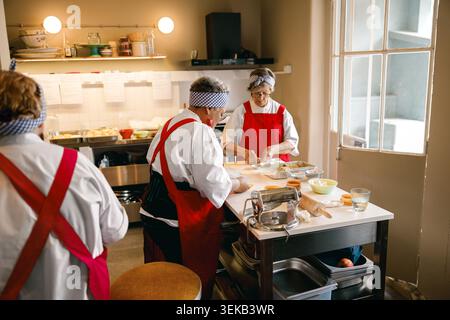 Three senior Caucasian women preparing fresh dough for pastries in a kitchen Stock Photo