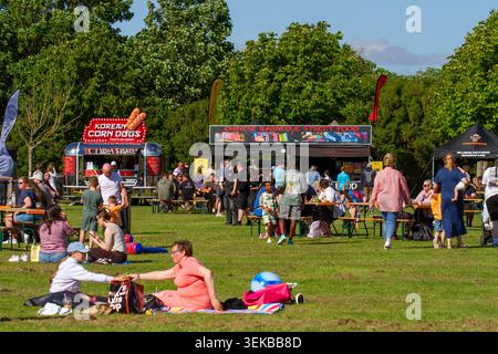 A busy outdoor summer food festival in the UK featuring a Korean Corn Dogs catering trailer and a Chinese Barbecue Street Food stall. Southport, UK. Stock Photo
