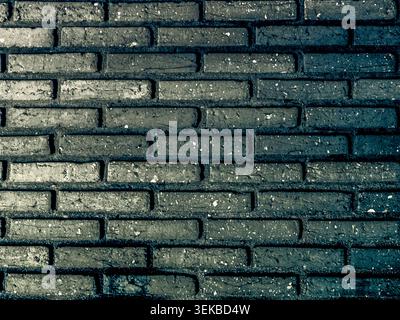 Detailed background of a dark teal or slate grey brick wall. The bricks have a weathered, rustic texture with white speckles and deep shadows, perfect Stock Photo