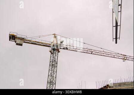 Tower crane at construction site against overcast sky Stock Photo