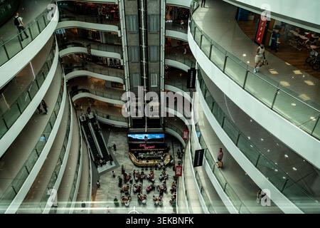 Interior of Toptani Shopping Mall in Tirana, Albania, featuring curved balconies, glass railings, escalators, and a central elevator shaft. Stock Photo