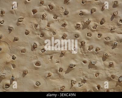 Mediterranean wall with embedded stones in plaster – repeating structure, ideal as background texture. Close-up. Copyspace. Stock Photo