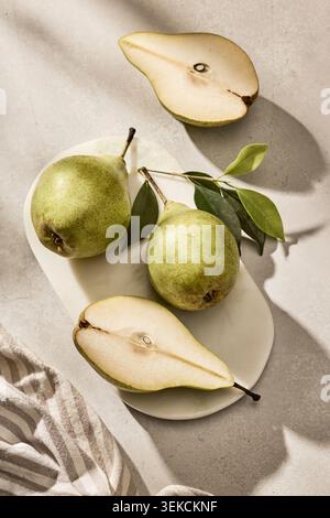 Overhead flat lay shot of fresh organic green pears, with two whole pears and one pear cut in half, arranged on a rustic  cutting board. The compositi Stock Photo
