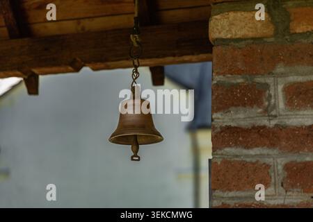 Serbia Valjevo 27.05.2026 Hanging Bronze Bell Beside Rustic Brick Column Stock Photo
