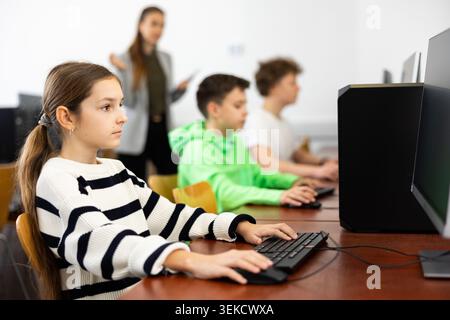 Pupils using computers at lesson, teacher teaching them in class room Stock Photo