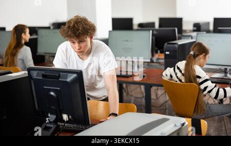 Focused teenager studying with classmates in computer lab Stock Photo