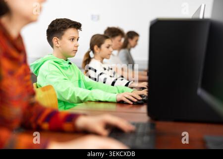 Pupils using computers at lesson, teacher teaching them in class room Stock Photo