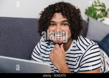 Young Indian man thinking while using laptop Stock Photo