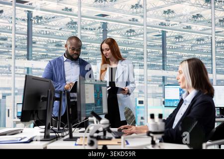 Scientists in microchip research facility conducting experiments to upgrade microelectronics. Workers doing bandwidth and latency calculations to improve semiconductors performance metrics Stock Photo