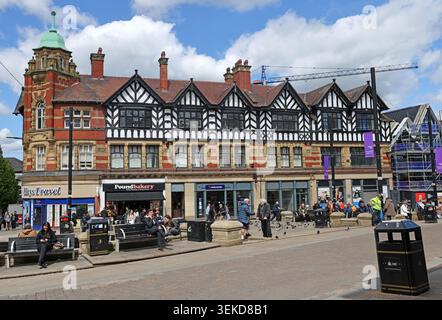 Sunny Wigan high street Market Place street scene showing shopfronts, benches, pigeons and mock Tudor town-centre architecture. Stock Photo