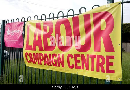 Large yellow Labour UK campaign HQ sign in Ashton-in-Makerfield, Wigan, Greater Manchester, with Community Fund banner nearby. Stock Photo
